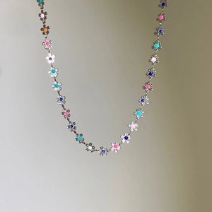 Gros plan détaillé des pétales de fleurs en émail coloré sur un collier argenté