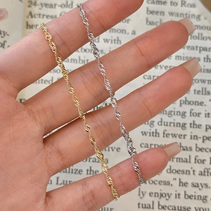 Vista detallada de finas cadenas de cuerda trenzada en oro y plata sobre fondo de libro