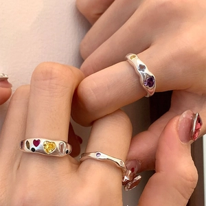 Unregelmäßiger Legierungsring mit bunten Zirkon-Herzen an der Hand eines Modells