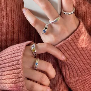 Nahaufnahme unregelmäßiger Silberringe mit bunten Zirkonsteinen an einer Hand