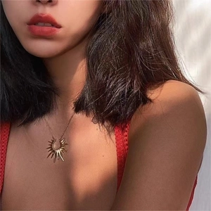 Close-up of golden sunflower pendant necklace worn by a model in bohemian style