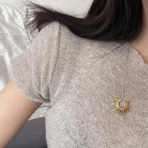 Detailed close-up of a gold-toned sunflower pendant on a delicate chain necklace