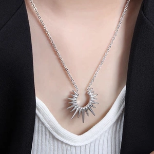 Close-up of a silver vintage sunburst pendant necklace on a neck with a black blazer