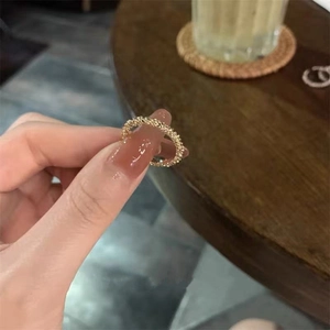 Close-up of golden woven texture ring with delicate granular finish worn on a finger