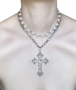 Detail einer mehrlagigen Perlenkette und Punk-Metallkette mit großem gotischem Kreuzanhänger