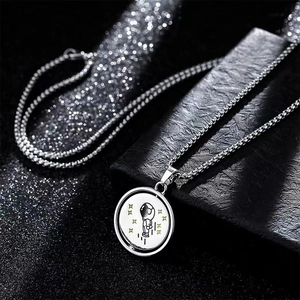 Macro view of silver astronaut pendant on box chain with sparkling bokeh light effects