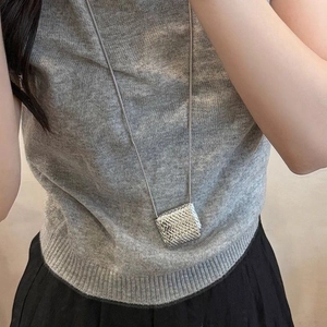 Silver woven mini bag pendant necklace on long snake chain for women worn on grey knitwear