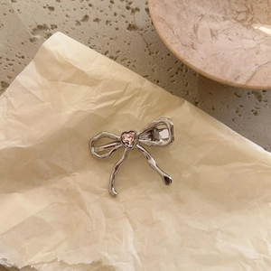 Eleganter silberner Haarschliff aus Metall mit rosa Herz-Strassstein auf gelbem Papier