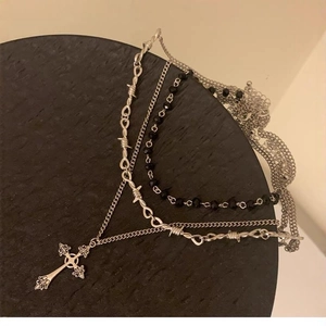 Dettaglio della collana multistrato gotica con perline nere e ciondolo a croce inciso
