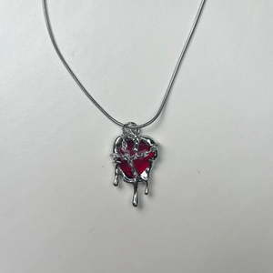 Macro shot of punk style molten lava heart pendant with red resin and silver chain