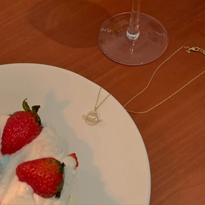 Elegant gold Saturn pendant necklace with sparkling zircons on a white ceramic plate
