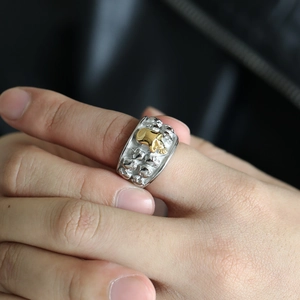 Detail of gothic skull ring with silver embossed skulls and a gold center skull on model