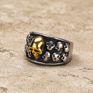 Detail of gothic stainless steel ring with vintage skull relief and gold accent skull
