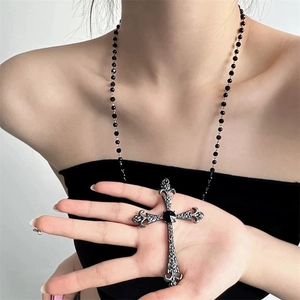 Gros plan d'un collier croix gothique avec une gemme noire et des détails ciselés