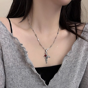Nahaufnahme der gotischen Kreuzkette mit Dornenreben und roter Rose am Hals