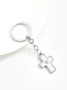 Macro shot of silver alloy double cross keychain pendant on white decorative plate