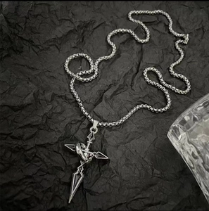 Détail du collier pendentif croix en acier titane avec anneau sur fond noir froissé