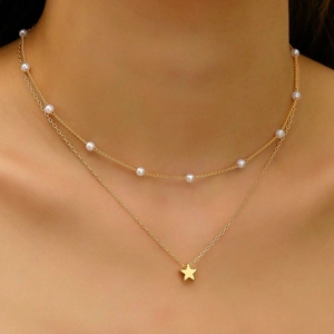 Detail of double-layered gold necklace featuring pearls and a star pendant on a model