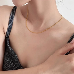 Close-up of a minimalist gold chain necklace on a model collarbone area