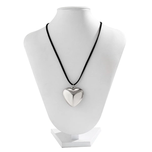 Macro shot of 3D metallic heart pendant with polished silver finish on a black cord