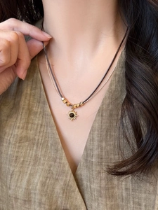 Dettaglio della collana a strati con girasole dorato e occhio di tigre indossata da una modella