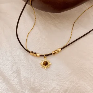 Collana a doppio strato girasole dorato con pietra occhio di tigre su lino bianco