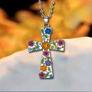 Primer plano del colgante de cruz con flores de esmalte de colores y diamantes de imitación