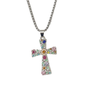 Detalle de un collar de cruz de plata con flores esmaltadas de colores y gemas finas
