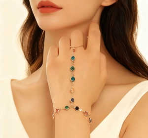 Detalle de la pulsera de anillo de oro con gemas redondas de colores en la mano femenina