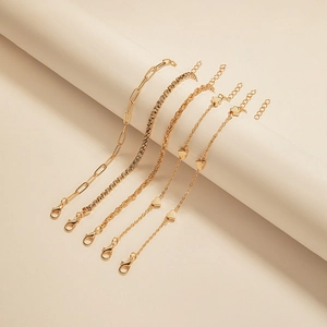 Detailed close-up of a five-piece gold bracelet set featuring heart charms and crystal chains