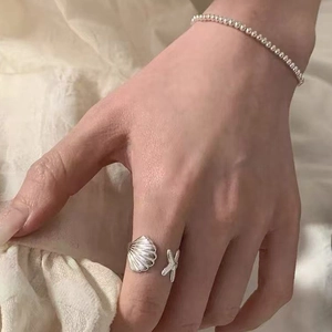Dettaglio dell'anello con conchiglia e stella marina con bracciale sulla mano