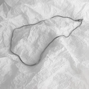 Collier chaîne serpent carrée argentée minimaliste sur fond blanc esthétique
