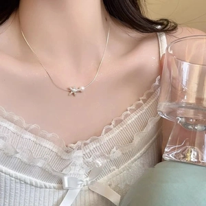 Close-up of elegant silver starfish necklace with pearl pendant on model neck
