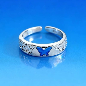 Macro detail of silver butterfly ring with blue wings and vintage filigree pattern