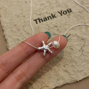 Minimalist starfish necklace with white pearl pendant on a delicate silver metal chain