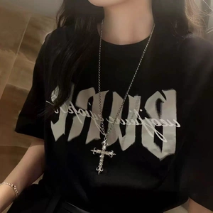 Close-up of gothic cross pendant necklace with sparkling stones on a black T-shirt