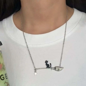 Dettaglio della collana creativa con gatto strega su scopa su una maglietta bianca