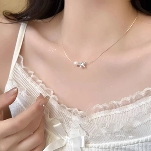 Detailed close-up of a golden starfish pendant with a white pearl on a delicate necklace