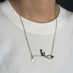 Dettaglio di un gatto vintage seduto su un ciondolo a scopa d'argento con collana