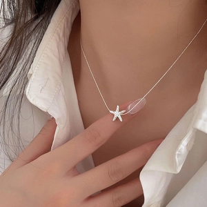 Close-up of a silver starfish pendant necklace on a woman wearing a white shirt