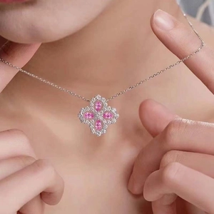 Detailed view of a four-leaf clover necklace with pink pear-shaped stones on skin