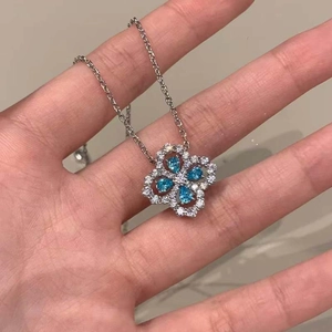 Elegant silver four-leaf clover necklace with blue gemstones and sparkling white crystals