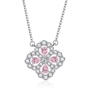 Macro detail of a four-leaf clover necklace with pink teardrop stones and micro-pave crystals