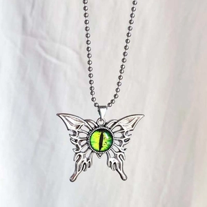 Detalle del colgante de mariposa gótica con ojo de demonio verde y cadena de plata