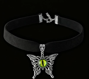 Detalle del choker mariposa gótica con colgante ojo verde sobre banda de terciopelo