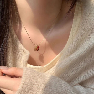 Dettaglio della collana con ciondolo melograno vintage su un maglione beige in maglia