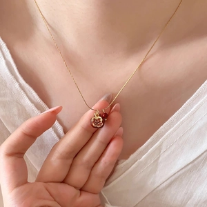 Dettaglio della collana dorata vintage con ciondolo a melograno rosso scuro e perla