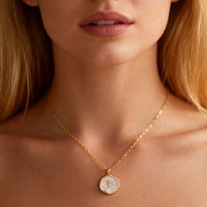Detailed close-up of a vintage colorful enamel cross necklace worn by a female model