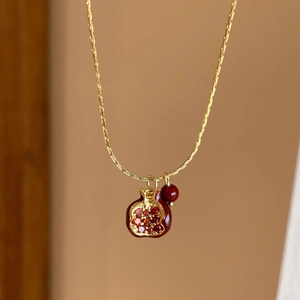 Elegante collana a melograno dorata con cristalli rossi e perla su una catena sottile
