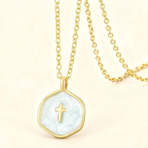 Golden necklace with blue enamel hexagonal cross pendant on elegant beige background